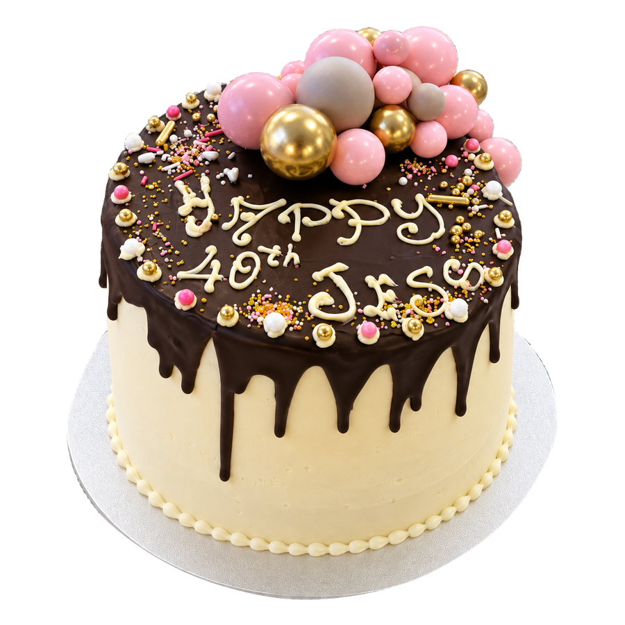 Chocolate drip cake topped with pink and gold spheres